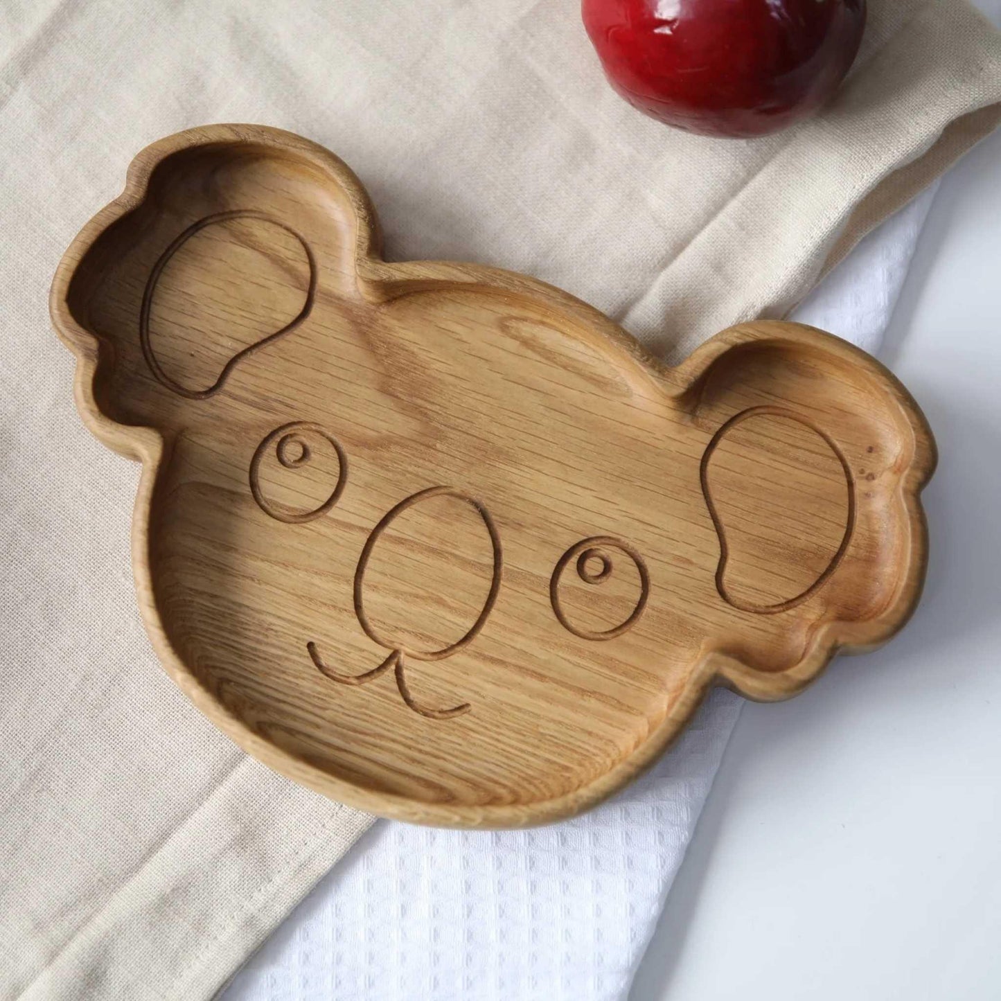 Wooden koala-shaped tray on a white and beige fabric background