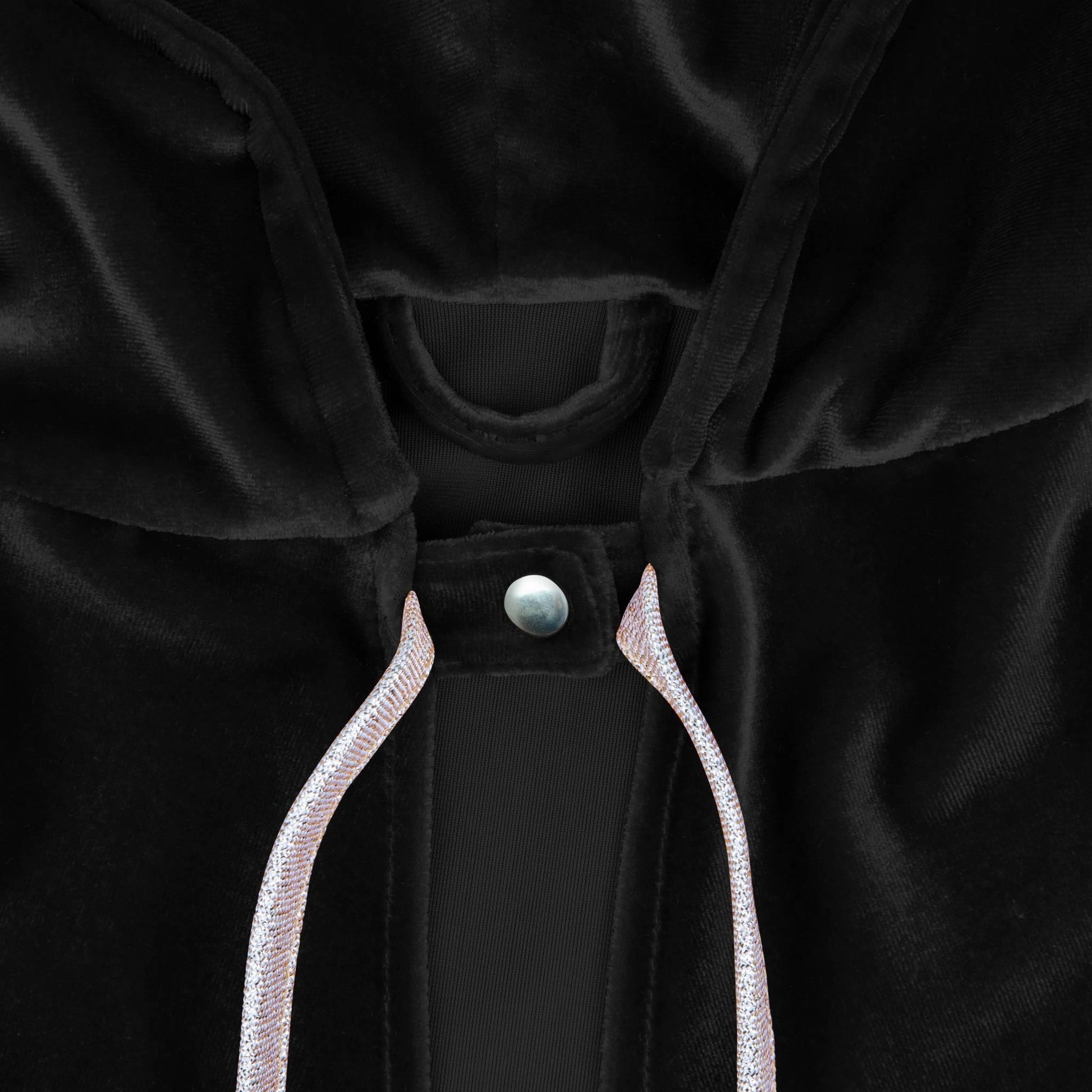 Close-up of a black garment with a button and white trim on a dark background