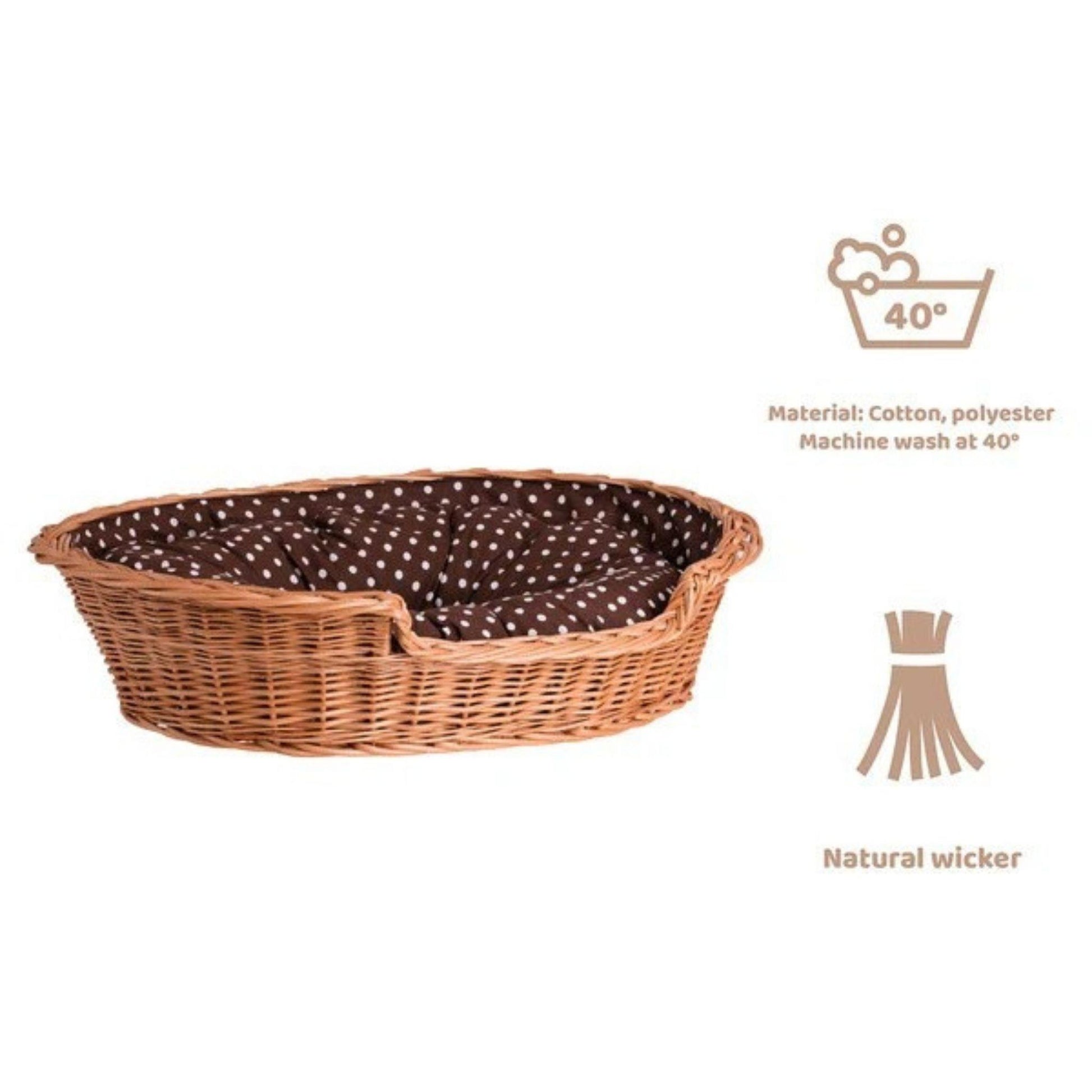Wicker pet bed with brown and white polka dot cushion on a white background