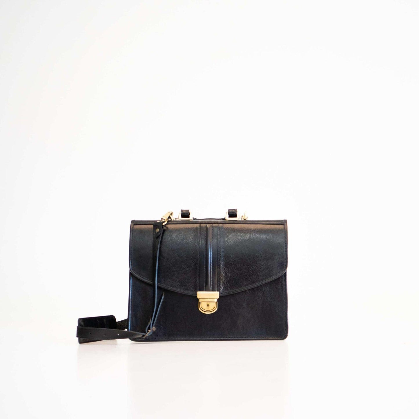 Black handbag with gold clasp on a white background