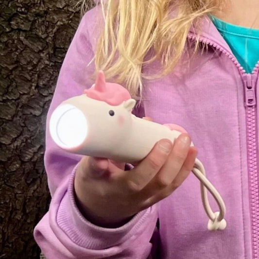 Child holding a unicorn-shaped flashlight against a tree background