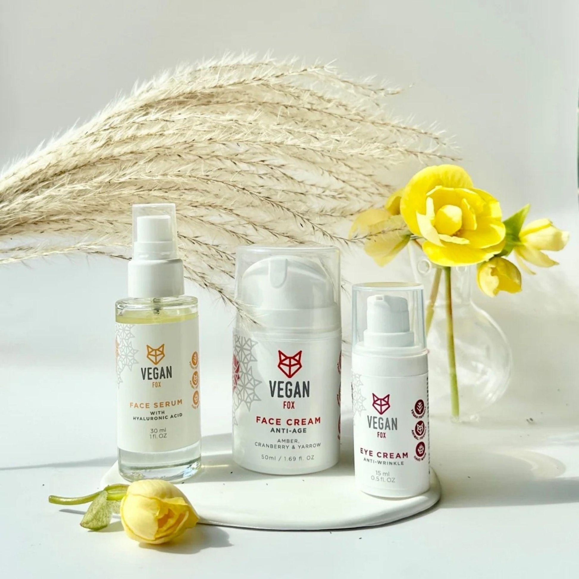Three vegan skincare products on a white surface with decorative elements.